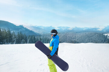 Wall Mural - Snowboarder Of Man At Ski Resort On The Background Blue Sky,  Hold Snowboard. Wearing Ski Glasses. Ski Goggles  With The Reflection Of Snowed Mountains