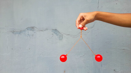 kid holding lato-lato. a traditional toy consisting of two heavy pendulums made of plastic and suspe