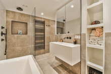 A Modern Bathroom With Beige Tiles And White Fixtures On The Walls, Along With A Glass Shower Stall In The Corner