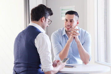 Wall Mural - Young business man sitting at table talking.