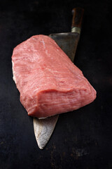 Wall Mural - Raw cap of rump calf offered with a knife as close-up on a black board with copy space