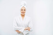 © VK Studio - Beautiful smiling young woman has soft healthy skin after taking shower, wears bath robe and towel wrapped on head, enjoys spare time at home, isolated over white background. Wellness concept.