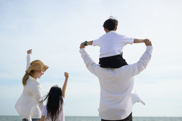 Wall Mural - Happy family spending time together at beach, Father give son piggyback on the beach, Father carrying his son with blue sky view, Holiday and travel concept