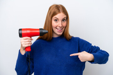 Wall Mural - Young redhead woman holding a hairdryer isolated on white background with surprise facial expression