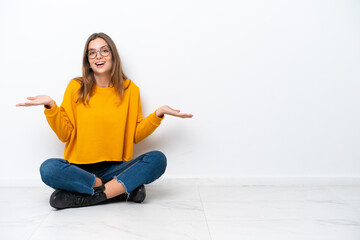 Wall Mural - Young caucasian woman sitting on the floor isolated on white background with shocked facial expression