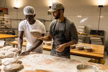 Wall Mural - Bakers school, master baker kneading bread dough on the table with flour, teaching the technique to his apprentice 