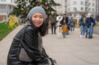 outdoors urban portrait of young happy and beautiful Asian Korean woman in leather coat and beanie taking a walk relaxed in city business district smiling cheerful