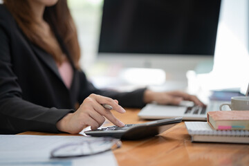 Fototapete - Closed up with female accountant hand use calculator and work with data paper, business, and finance concept.
