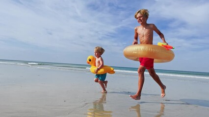 Wall Mural - Two happy boys run with inflatable buoys doughnut and duck