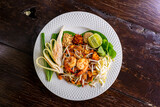 Fototapeta Tęcza - A delicious and colorful plate of pad thai, a popular Thai noodle dish, captured from above. This pad thai stock photo would be perfect for any food-related project, such as a restaurant menu.