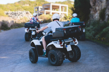 Wall Mural - Group of riders riding ATV vehicle crossing mountain serpentine road track, process of driving rental vehicle, all terrain quad bike vehicle, during off-road tour, Greece, Ionian sea islands