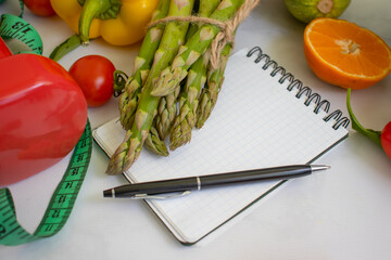 Wall Mural - Notepad, dumbbell, vegetables and fruits on a light background