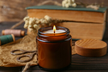 Wall Mural - Burning scented candle, book and flowers on wooden table, closeup