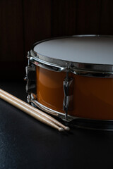 Drum stick and drum on black table background, music instrument concept