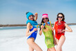 © Михаил Решетников - Three female friends in swimsuits drink blue alcoholic cocktails on a snowy beach. Hot girls posing in bikinis outdoors in winter.