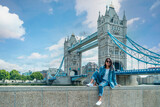 Fototapeta Londyn - Asian women on a city trip in London by the river Thames at the famous places in London, Tower Bridge during summer