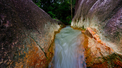 Close-up view of river water flowing from the gap between two large rocks