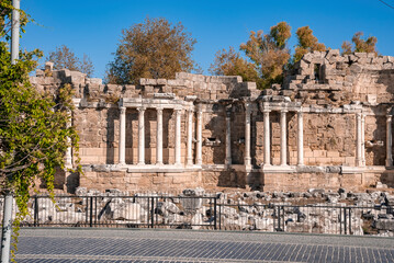 Wall Mural - Ruins of columns and walls of Nymphaeum fountain at ancient Side in Turkey with trees and clear blue sky in the background during sunny day