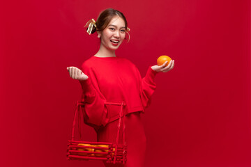 Young asian woman wearing red sweater dress with mandarin orange on red background for Chinese new year festival