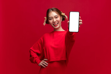 Young asian woman wearing red sweater dress show smartphone with empty screen on red background for Chinese new year and Christmas festival
