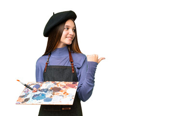 Wall Mural - Young artist man holding a palette over isolated chroma key background pointing to the side to present a product