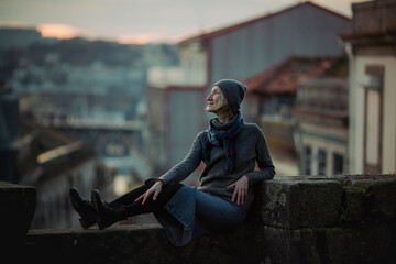 Sticker - A woman sits on an stone wall at dusk in Porto downtown, Portugal.