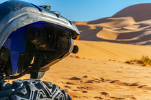 A Four Wheeled Quad Front Part Blue And Black Color Vehicle Parked  In The Sahara Desert, Selective Focus In Foreground, Sunny Day With Golden Yellow Colored Sand Dunes And Blue Sky In Blur Background