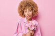© WHstudio Leushin N - Indoor shot of roamantic lovely woman with curly fair hair holds gerbera flowers receieves bouquet from boyfriend or colleagues on her birthday wears elegant shirt isolated over pink background