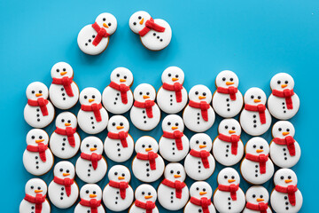 Wall Mural - Gingerbread snowmen covered with icing on a blue background, flat lay.