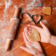 Biscuit, cookie as heart out of dough on hands of child . Heart molds, rolling pin and flour on a table. Valentines Day celebration.