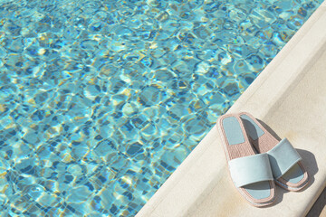 Wall Mural - Stylish slippers near outdoor swimming pool on sunny day, space for text