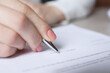 © New Africa - Woman signing document at table in office, closeup