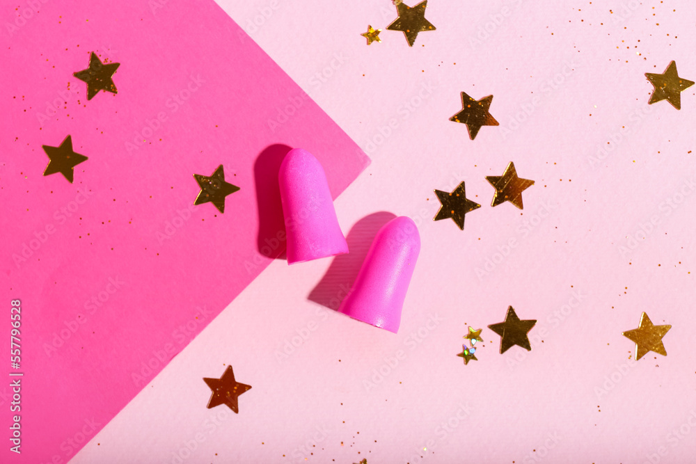 Foam earplugs and golden sequins on pink background