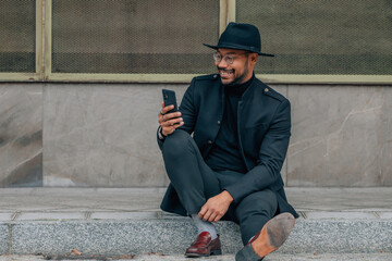 Wall Mural - latin man with mobile phone sitting on the street