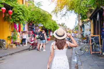 happy traveler sightseeing at Hoi An ancient town in central Vietnam, woman with dress and hat traveling. landmark and popular for tourist attractions. Vietnam and Southeast Asia travel concept