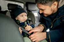 Smiling Father Fastening Car Seat Belt For Son