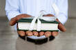 © Westend61 - Hands of man holding book tied with white ribbon