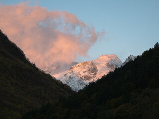 Wall Mural - Pink clouds illuminated by the evening sun over the snow mountain. Cumulus pink colored clouds over the winter mountains.