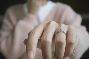 Wall Mural - Close up of an elegant engagement diamond ring on woman finger with pink sweater winter clothe. love and wedding concept. Soft and selective focus.