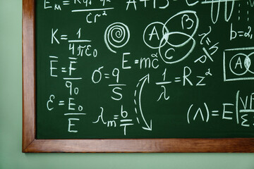 Wall Mural - Blackboard with different physical formulas written with chalk on light green wall