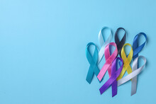 Stack Of Colorful Awareness Ribbons On Blue Background With Copy Space. World Cancer Day Concept. 