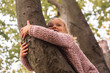 © Alex - Smiling blond girl child lies hugging a tree with two hands