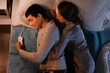 Young couple sleeping on electric heating pad in bedroom at night, top view