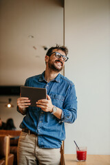 Wall Mural - Portrait of young adult smiling cheerful businessman indoors drinking smoothie morning routine starting day happy handsome successful entrepreneur freelancer checking his business tasks for the day.