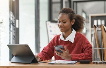 Wall Mural - Smiling African American Hispanic student looking up from laptop at campus library, using tablet and mobile