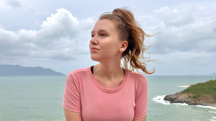 Portrait of beautiful girl, young happy woman at sea, ocean background, enjoying summer sunny day, vacation on mountain, smiling in tropical country, have fun