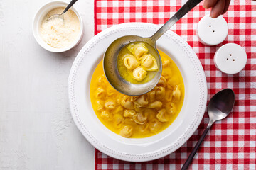 Wall Mural - Ladle with tortellini in beef and chicken broth. Serving egg pasta originally from the Italian region of Emilia, Bologna. Stuffed with a mix of meat, prosciutto, mortadella, hard cheese, egg 