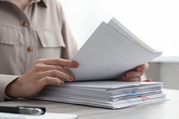 Woman reading documents at wooden table in office, closeup