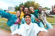 © Davide Angelini - Multiracial group of friends taking selfie picture walking on city street - Happy young people smiling together at camera outside - University students having fun in college campus - Youth culture