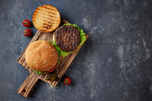 Tasty Homemade Grilled Burger With Beef, Cheese, Tomatoes, Pickles, Onion And Lettuce On A Dark Concrete Background With Copy Space. Top View Flat Lay. Fast Food And Junk Food.